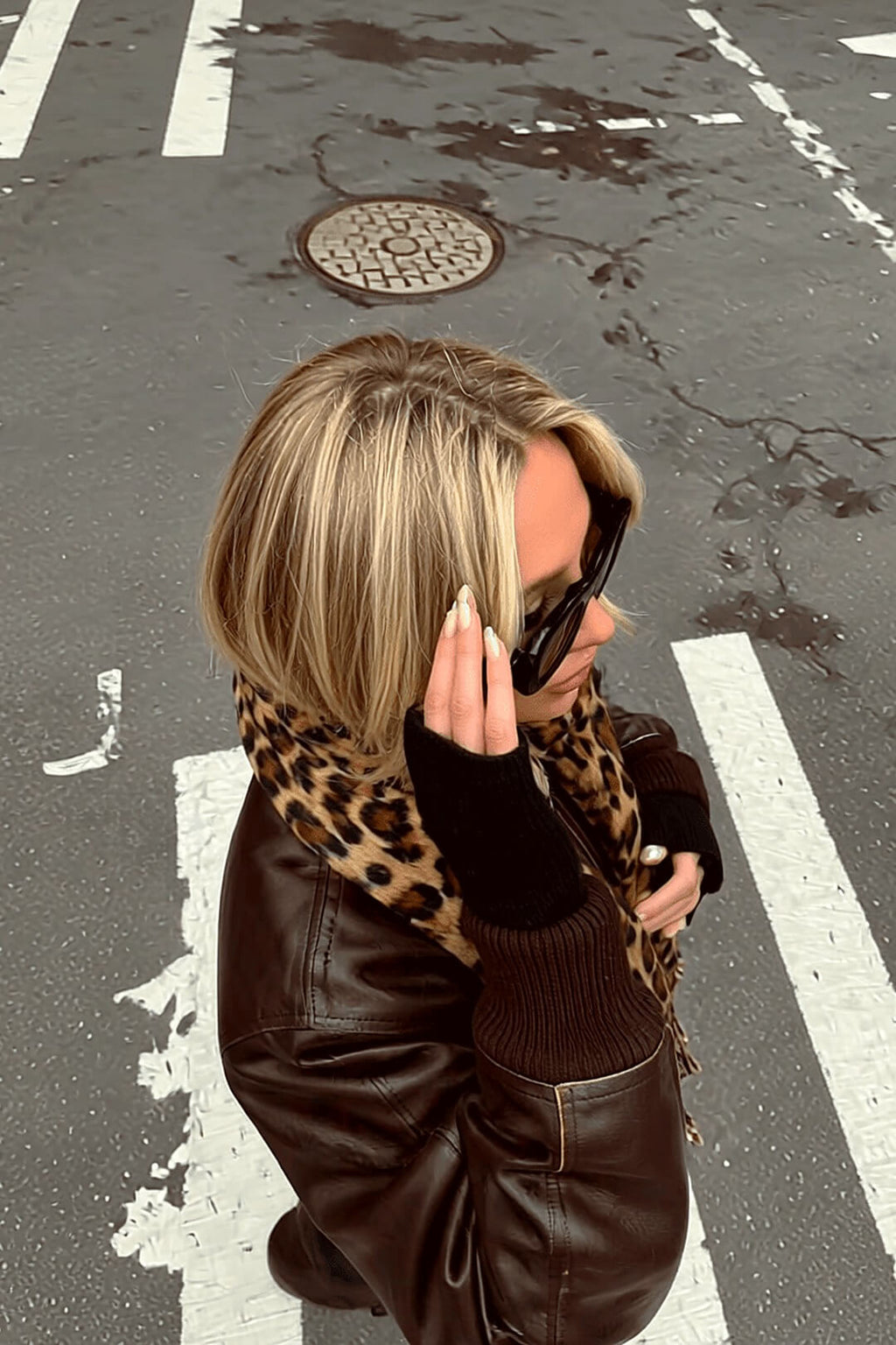 Marais leopard scarf and brown bomber from an overhead angle, candid phone-call moment — Amavé street style.