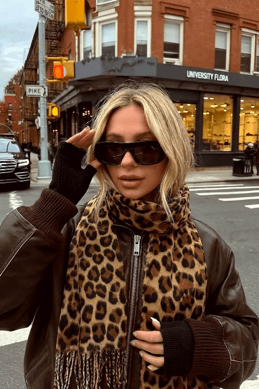 Marais leopard hooded scarf with a brown leather bomber on an urban street corner, golden hour — Amavé.