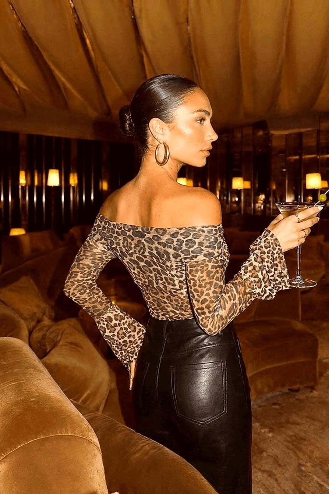 Marseille leopard Bardot in a draped golden lounge, profile pose with martini in hand — Amavé after-dark editorial.